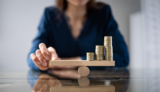 balancing financial risk - an image with a lady, balancing with her finger a scale with coins