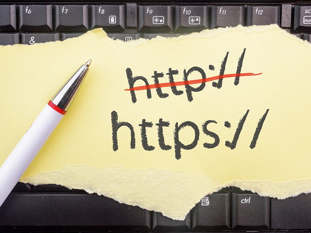Надпис HTTP, заменен с HTTPS върху лист хартия пред компютърна клавиатура.